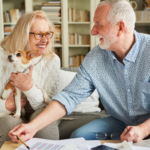 April 25 Events Page Image - Beach House Elderly man and his wife smiling and holding small dog