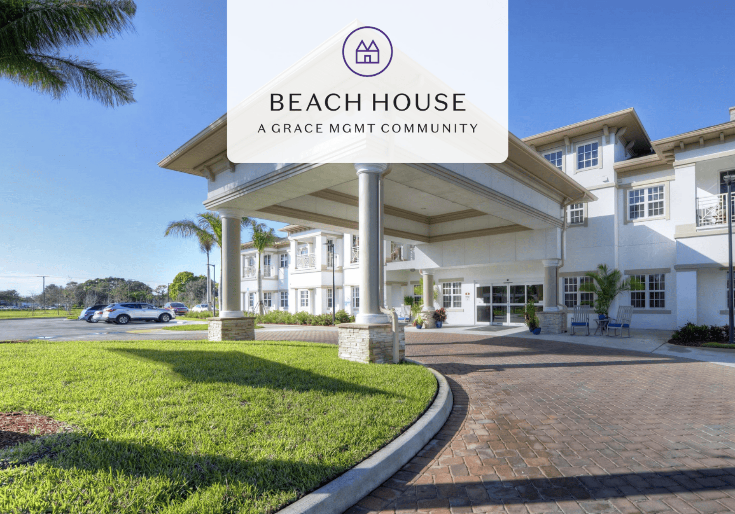 White hotel-style building with a covered entrance, palm trees, and a brick driveway under a blue sky; overlay reads Beach House.